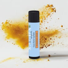 Load image into Gallery viewer, Lip balm in front of turmeric powder flying around