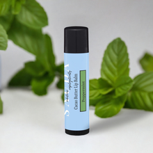 Load image into Gallery viewer, Lip balm tube in front of peppermint leaves
